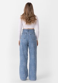 Lichtblauwe, high-waisted jeans met een wijde pijp, voorzien van sterrenpatronen, vijf zakken en rafelige zoomdetails.