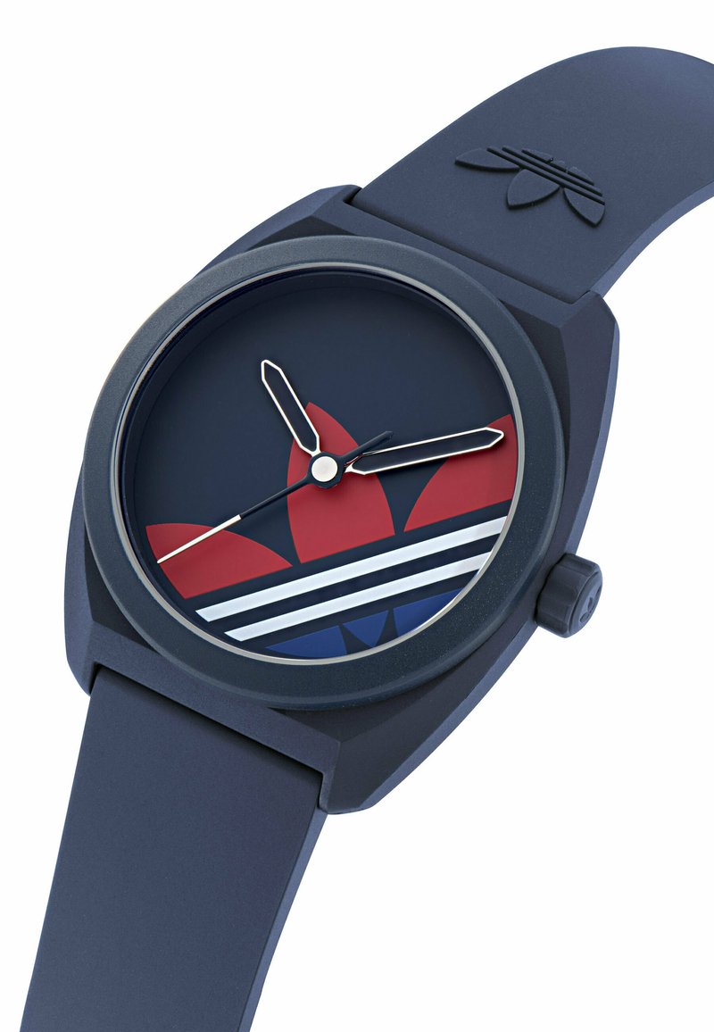 Navy blue wristwatch with Adidas trefoil logo on dial, white hour and minute hands, red and blue design elements, and rubber strap.