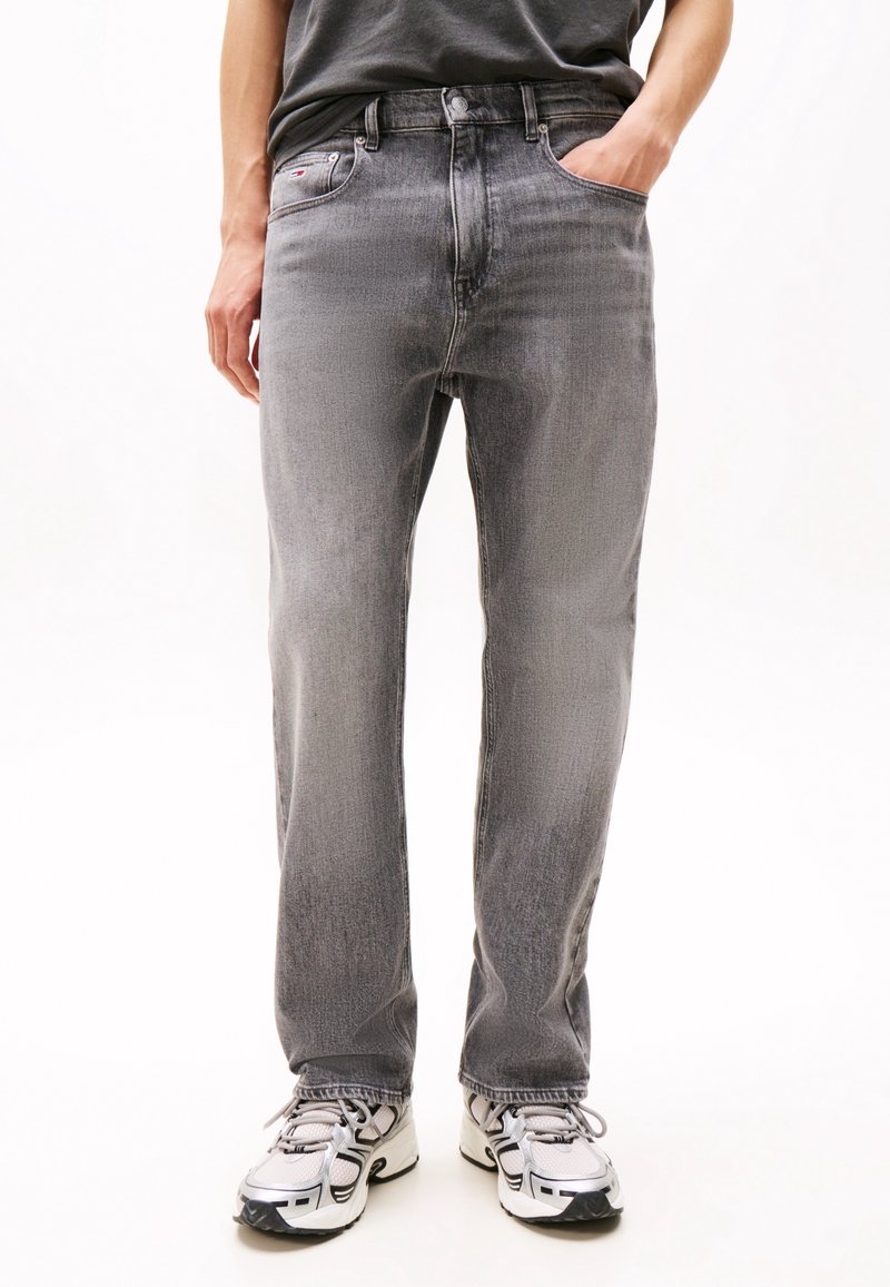 Grå denimjeans med rak skärning och subtila slitningar. Matchade med grå sneakers som framhäver den avslappnade stilen.