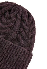 Sötétlila gyapjúból készült kötött sapka, tetején texturált kábelmintával és alul bordázott szegéllyel. Puha, vastag anyag.