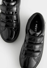 Svarta patentlädersneakers med tre kardborreband, rund tå och texturerad sidostygn. Inuti finns storleksmärke.