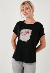 Zwart T-shirt met korte mouwen en een bloemig grafisch ontwerp in wit en rood. Relaxte pasvorm met een ronde halslijn en een zachte stoftextuur.