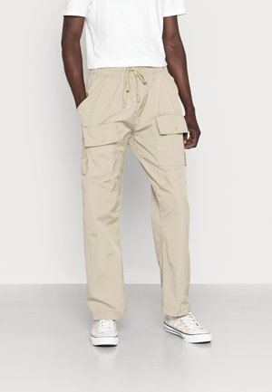 Pantalones cargo beige con un corte holgado, cintura ajustable con cordón y múltiples bolsillos laterales. Fabricados en un tejido ligero, aptos para uso informal.