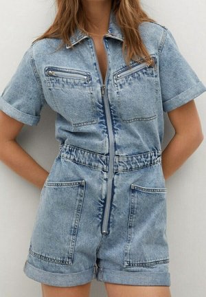 Kvinde iført lyseblå denim kortærmet romper med lynlås foran, opsmøgede ærmer og shorts samt fire store lommer.