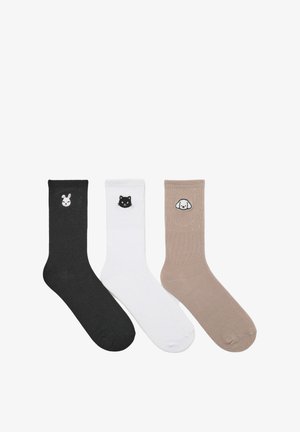 Tre paia di calzini a coste: neri con un design di coniglio, bianchi con un gatto e beige con un cane. Ogni calzino presenta un ricamo di un animale distinto.
