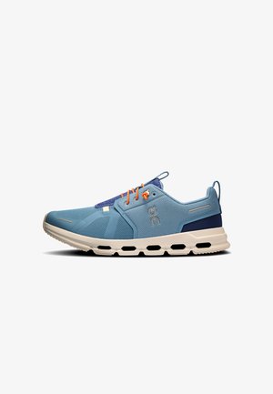 Lichtblauwe sportieve sneaker met oranje veters, ademend mesh bovenwerk, witte zool met zwarte ventilatiegaten en een marineblauw hielstuk.