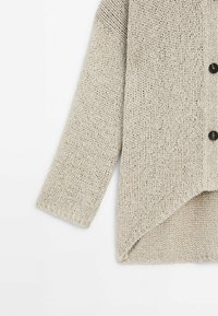Hellbeige gestrickte Strickjacke mit strukturiertem Design, abgerundetem Saum, langen Ärmeln und schwarzen Knöpfen.