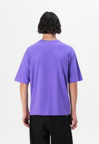 Purple oversized t-shirt made of cotton, featuring a crew neckline and short sleeves. Smooth texture with a relaxed fit.