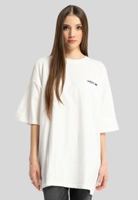 Biała, oversize'owa koszulka bawełniana z haftem "LUCKY ME" w kolorze czarnym na lewej piersi. Krótkie rękawy i luźny krój.