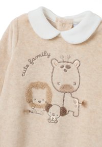 Conjunto de bebé beige con cuello blanco, que presenta un león, un elefante y una jirafa de dibujos animados bordados, junto con el texto "familia adorable".