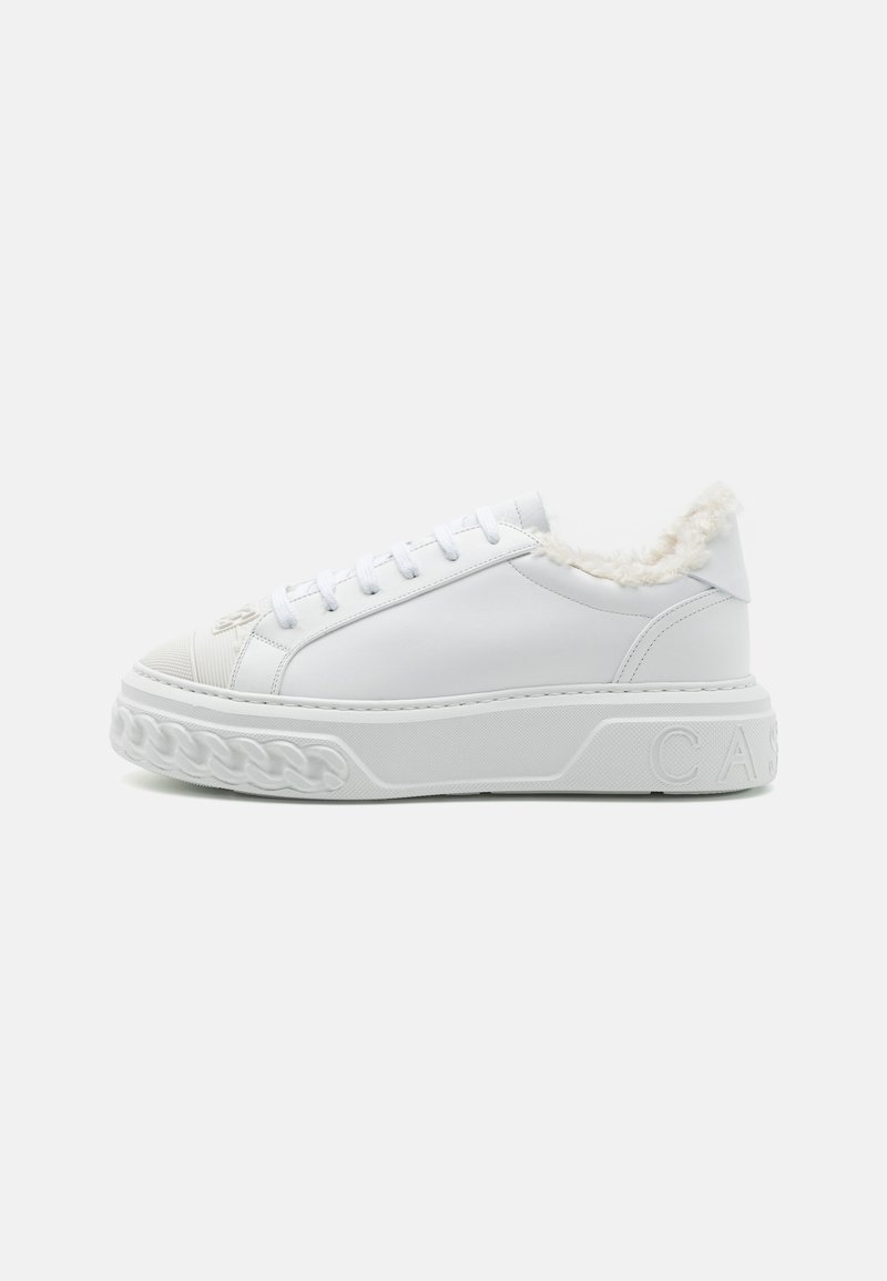 White sneakers made of smooth synthetic material with a textured sole, featuring a fluffy lining at the ankle and embossed branding on the side.