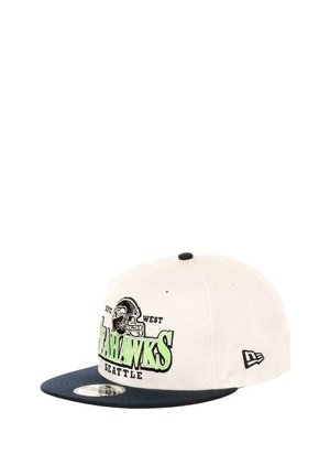 White baseball cap with a navy brim, featuring "SEAHAWKS" in green and black logo embroidery. Includes adjustable strap and ventilation eyelets.