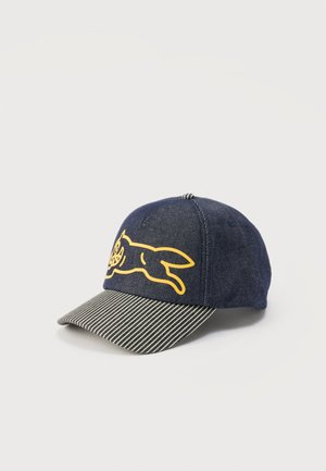 Mørkeblå denimlue med en gul omriss av en løpende katt på forsiden og en svart-hvitt stripete brem.