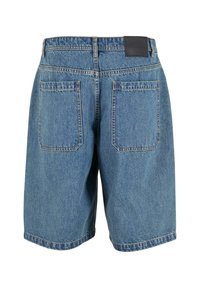 Denim shorts med mellemhøj talje, lys blå farve og to baglommer. Har et sort logo-patch på bagbuksen.