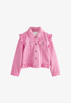 Glunderend meisje dat een roze jasje draagt over een t-shirt met eenhoornprint, een sprankelende lichtroze rok, witte sokken en witte hoge sneakers.