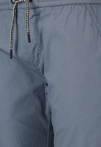 Ljusblå shorts gjorda av tyg med en slät textur, med en svart och vit flätad dragsko och sidofickor.