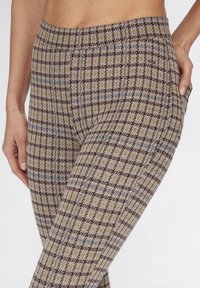 Bruine en beige geruite legging met een textuurstof; heeft een kleurrijk ruitpatroon en een elastische tailleband.