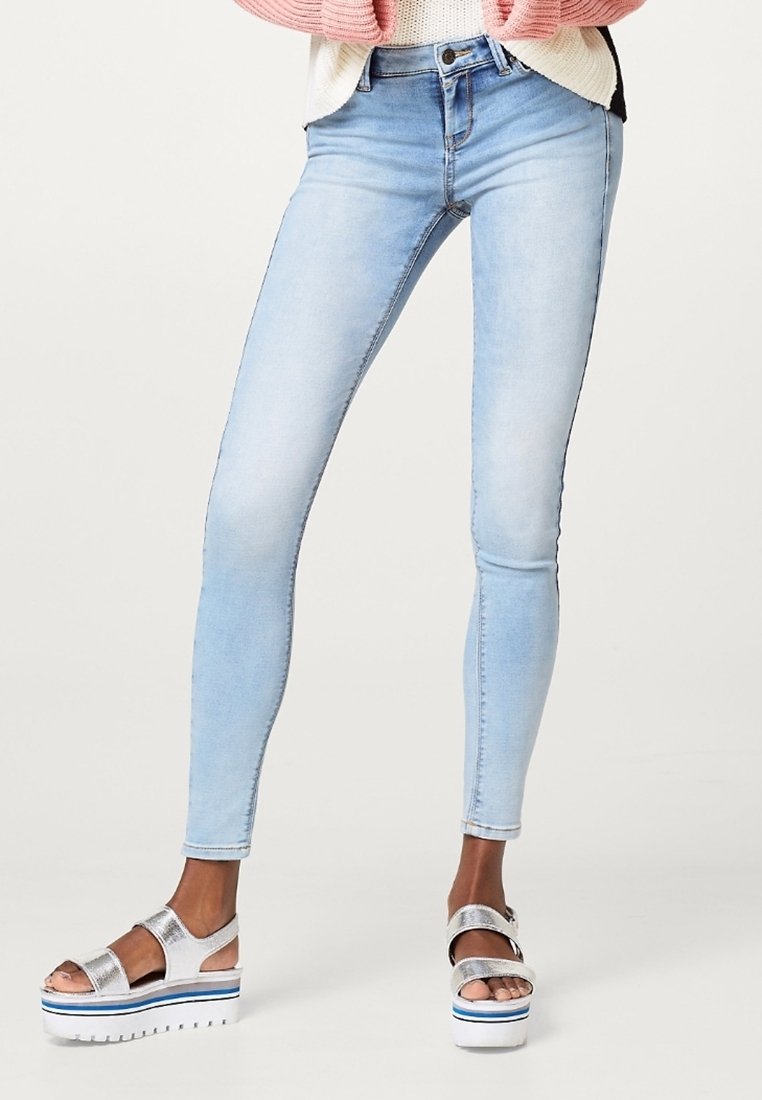 Vaaleansiniset kapeat farkut, jotka on valmistettu denimi-kankaasta ja joissa on sileä pinta sekä korkeavyötärö, yhdistetty hopeisiin korokepohjaisiin sandaaleihin.