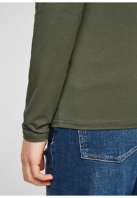 Lange mouwen shirt in olijfgroene katoen met een zachte textuur, aansluitende manchetten en een rechte zoom. Draag het met blauwe denim jeans.