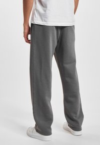 Grå sweatpants med løs pasform, lavet af blødt materiale. Lige ben med sidesømme, parret med hvide sneakers. Casual design.