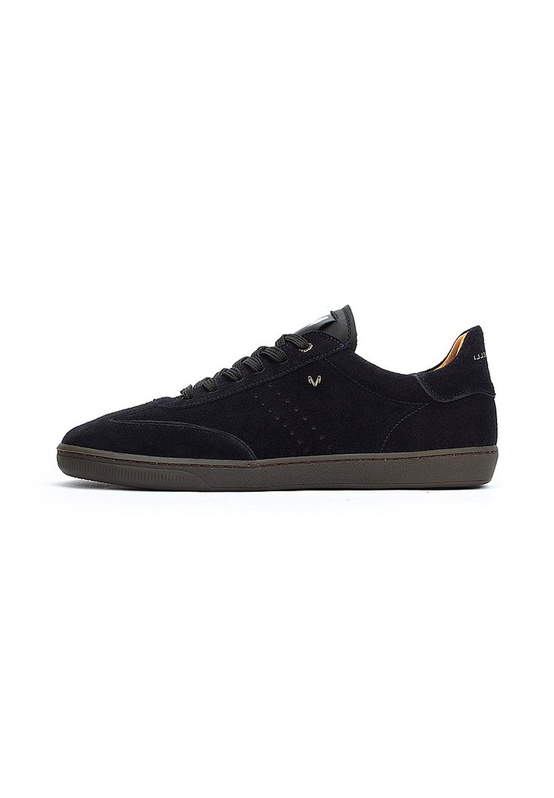 Zapatillas de ante negro con diseño de caña baja, cierre con cordones, suela de goma gris y sutiles perforaciones en el lateral.
