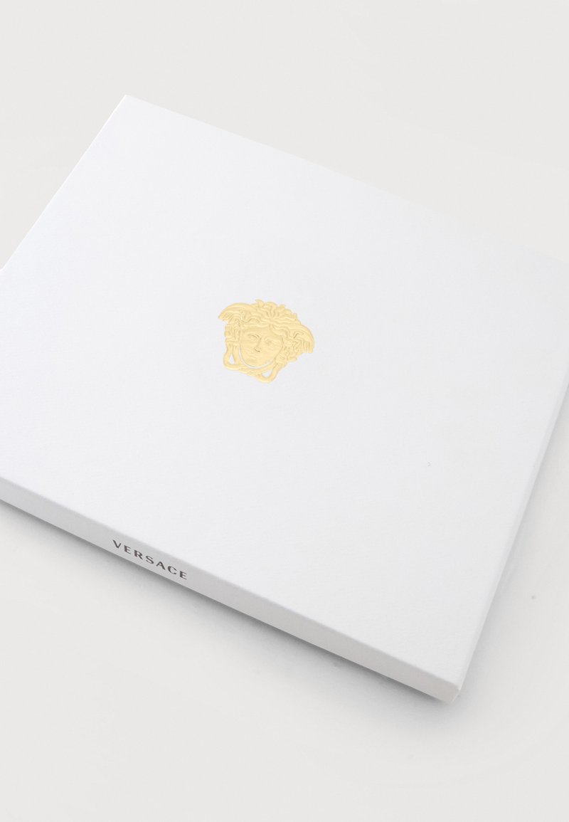 White rectangular Versace box with a gold Medusa head logo embossed in the center on a light surface.