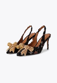Talons aiguilles en velours noir avec bouts pointus et talons de 10 cm. Chaque chaussure est ornée d'un nœud en sequins dorés.