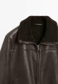 Mørkebrun læderjakke med tyk shearling-krave og central lynlåslukning mod hvid baggrund.