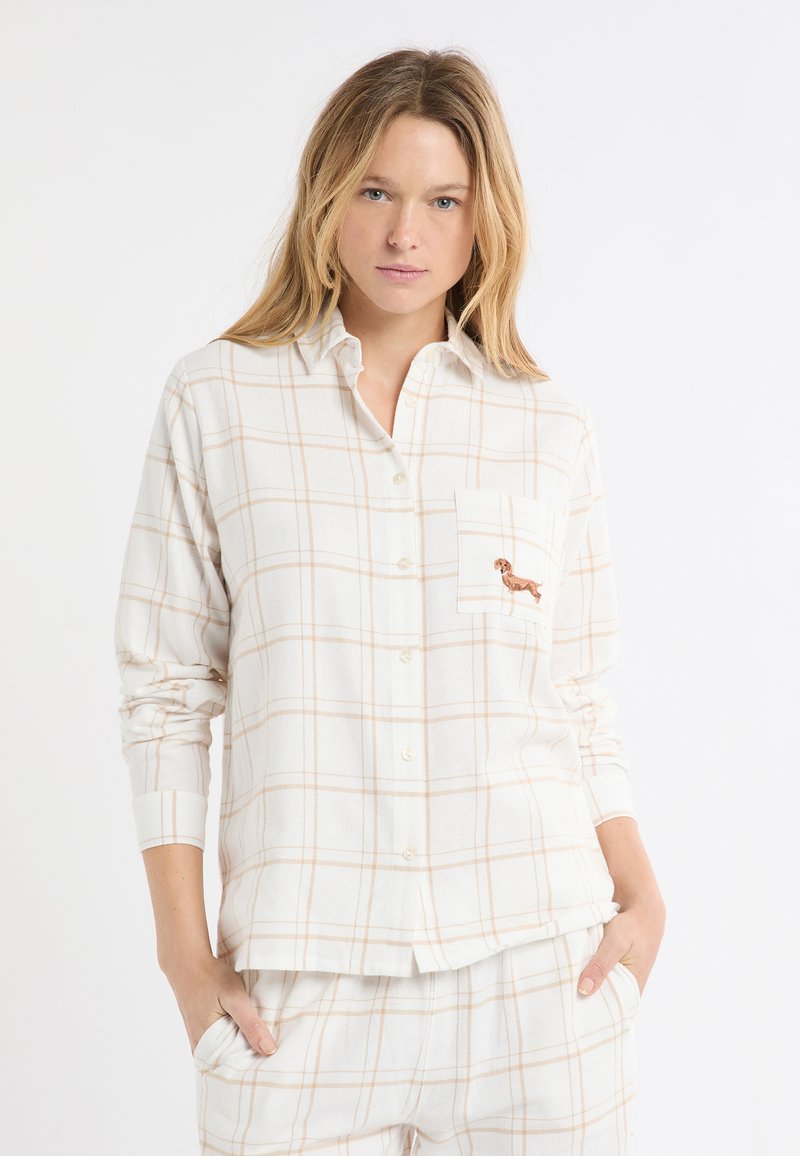 Biała flanelowa koszula w brzoskwiniową kratę, z przodem zapinanym na guziki oraz kieszenią na piersi ozdobioną haftowanym wzorem jamnika. Długie rękawy.