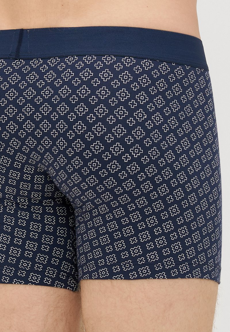 Navy blue boxer shorts with a white geometric pattern. Features a comfortable elastic waistband and soft fabric texture.