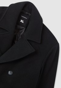 Cappotto di lana nero con ampio colletto e bottone nero, con etichetta di taglia "TERRANOVA XL" all'interno del colletto.