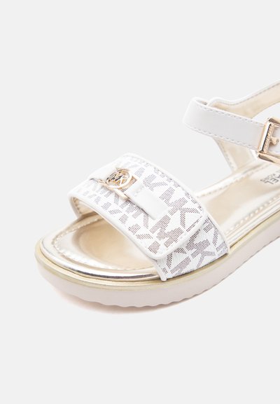 Λευκό σανδάλι με ρυθμιζόμενο λουράκι αστραγάλου, αγκράφα σε χρυσό τόνο, εμπρόσθιο λουράκι με μοτίβο και έμβλημα λογότυπου, και μαλακή σόλα.