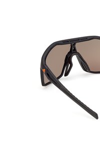Gafas de sol deportivas negras con acabado mate, grandes lentes marrones, diseño de marco angular y acento naranja en el lateral.