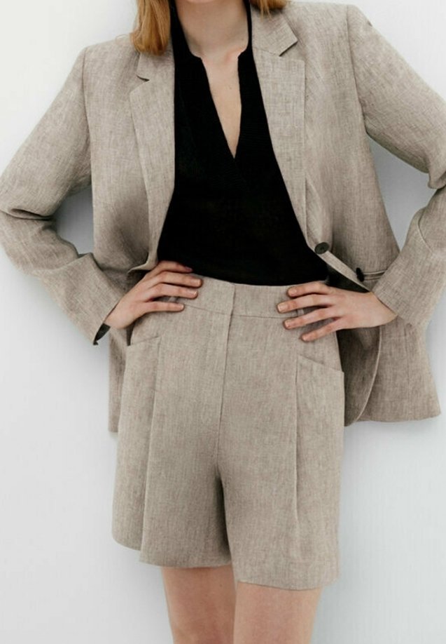 Beige linneblazer och matchande shorts med en texturerad finish. Blazern har en kilkrage, och shortsen har framfickor och veck.