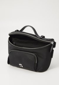 Black fabric bag with a zip closure, featuring a top handle, front zip pocket, and silver-tone hardware accents. Smooth texture, compact design.