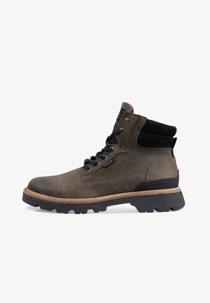 Brown leather ankle boot with black fabric accents, lace-up design, rugged sole, and contrasting wooden midsole. Features metal eyelets.