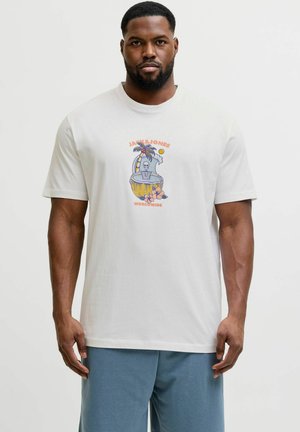 Muškarac nosi bijelu majicu s šarenim tropskim motivom kostura i natpisom "Jack & Jones Worldwide" sprijeda, uparenu s plavim kratkim hlačama.