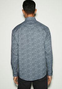 Camicia a maniche lunghe in tessuto blu scuro con un motivo paisley vorticoso. Collo classico e polsini con bottone. L'orlo è leggermente arrotondato.
