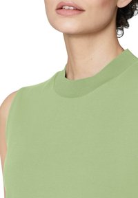 Lichtgroene mouwloze top met een geribbelde ronde hals. Effen textuur, slim fit ontwerp, zichtbare steken en schone snijkanten rond de halslijn.