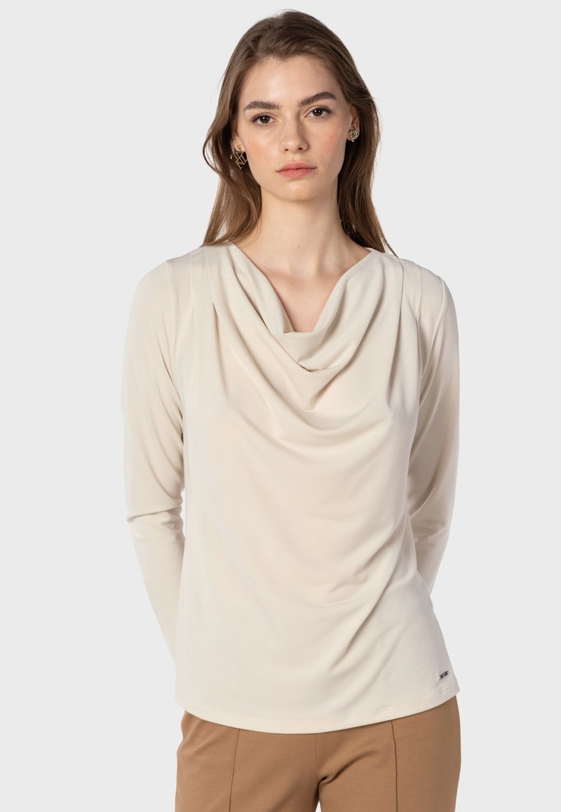 Hochgeschlossener Langarm-Top in hellem Beige, aus weichem Stoff mit Drapierung am Halsausschnitt und schmalen Ärmeln.
