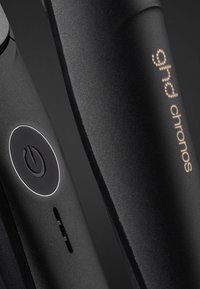 Zwarte haar stijltang met een strak ontwerp, aan/uit-knop met een verlichtingsring en het "ghd chronos" logo in een puntgouden lettertype.
