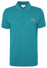Turkos polo skjorta i bomull med klassisk krage, korta ärmar och en liten grön och vit "Lacoste"-logotyp på vänster bröst.