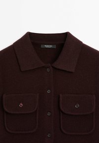 Cardigan en maille marron foncé avec col, fermeture boutonnée devant et deux poches poitrine à rabat boutonnées, étiqueté Massimo Dutti.