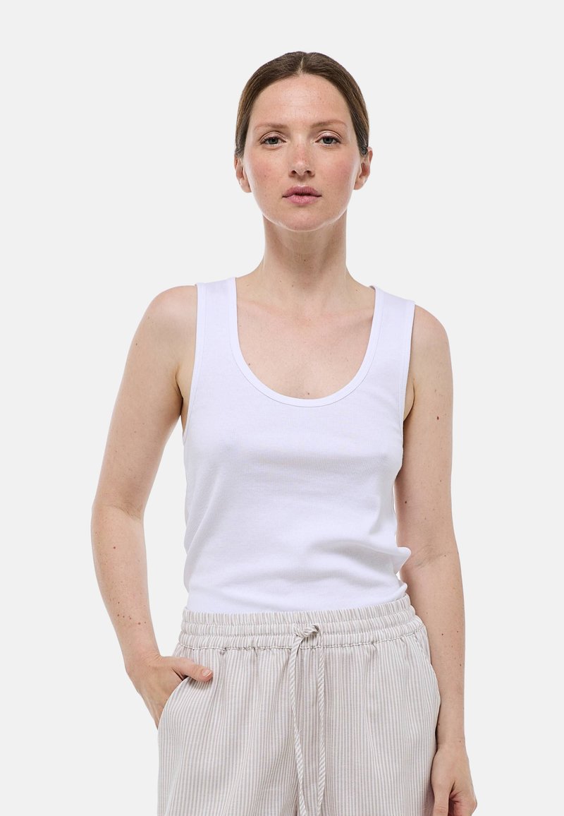 Débardeur en coton blanc avec un col rond et de larges bretelles, associé à un pantalon léger à rayures. Le tissu semble doux et décontracté.