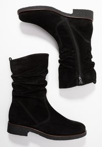 Bottines en daim noir avec un design ample, dotées d'une fermeture éclair sur le côté et d'une semelle texturée semblable au caoutchouc. Détails de couture minimalistes.