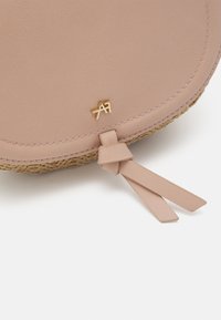 Borsa a mano in pelle rosa arrotondata con texture intrecciata nella parte inferiore, caratterizzata da un logo dorato e un dettaglio in pelle annodato.