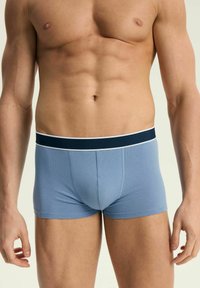 Jasnoniebieskie bawełniane bokserki z granatowym pasem wyposażonym w biały pasek. Gładka faktura, dopasowany krój i długość do połowy uda.