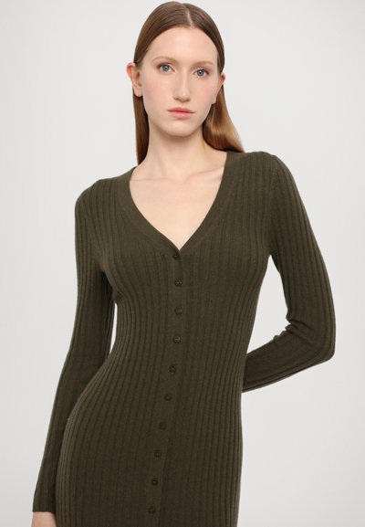 Rochie lungă cu mânecă lungă de culoare verde măslin, cu decolteu adânc în formă de V și nasturi în față. Materialul are o textură moale și modele verticale.