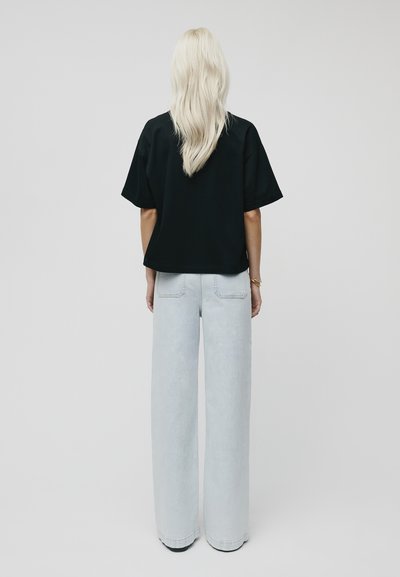 Black cropped t-shirt with wide short sleeves, paired with light-wash wide-leg jeans. Smooth texture, minimalistic design, no visible patterns.