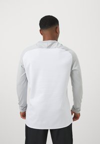 Langermige sportshirt met een witte body en grijze accenten op de schouders en mouwen. Glad fabric met een relaxte pasvorm.